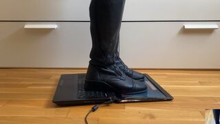 Leather riding boots crushing a laptop into pieces