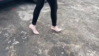 A girl in high-heeled shoes walks through liquid mud, into which her heels sink completely