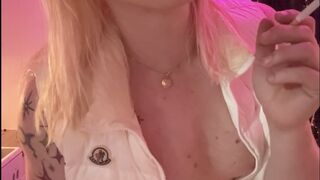 Transgirl smokes a cigarette in nothing but a white shiny down vest
