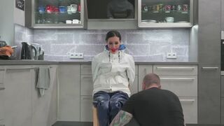 Miss Amira an einen Stuhl gefesselt in einem Farmerrain Regenanzug (behind the scenes)