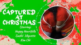 Captured At Christmas - Starring: Kim Chi, Sushi Xhyvette, Happy Heartfella - Kim and Sushii are magically bound and gagged by handsome elf Happy - Bondage Double Damsels Tied up Tape Gagged Rope Gag Talk Feet Socks