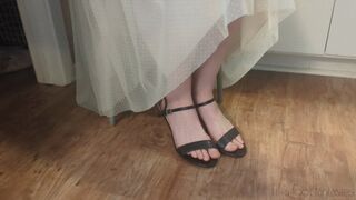 Fifi sitting in heels trying to scrunch her toes to free them from the toe strap