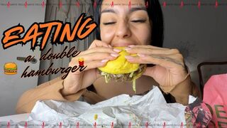 Eating a double hamburger.