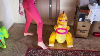 a girl barefoot in red tight jeans tramples two inflatable dinosaurs, puts her weight on them, presses foot fetish crash fetish legs jeans